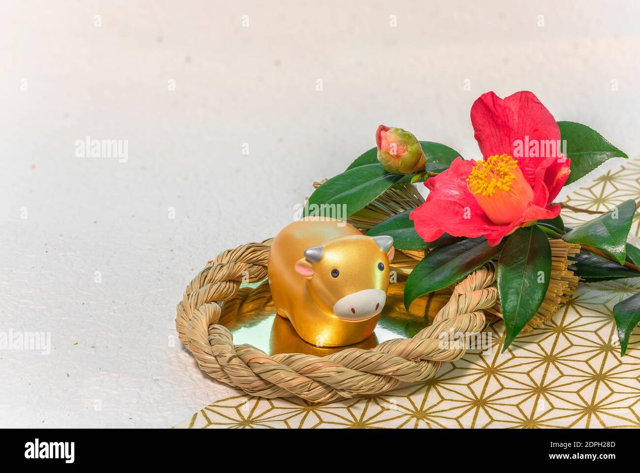 Biglietto d'auguri giapponese con un fiore Tsubaki chiamato l'inverno Rosa e una statuina animale zodiacale di vacca in a. Ornamento di paglia per l'anno della Ox Foto Stock