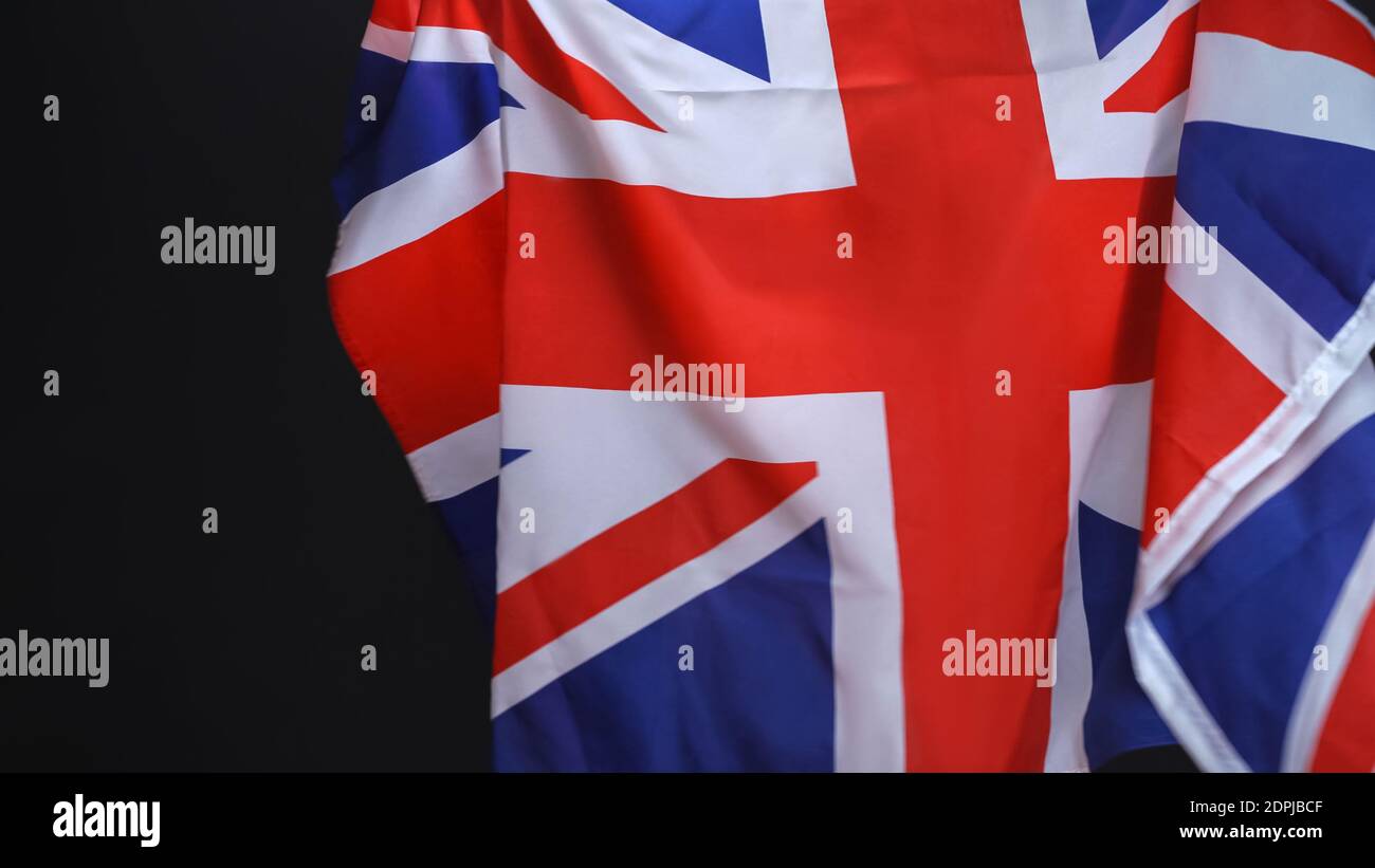 Nessuna persona visibile che detiene la bandiera dell'Inghilterra o del Grande La Gran Bretagna che celebra il giorno dell'indipendenza esprime patriottismo isolato su sfondo nero Foto Stock
