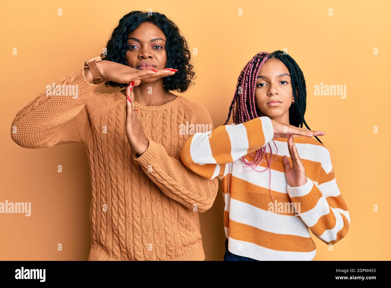 Bella madre afroamericana e figlia che indossa il maglione invernale di lana che fa il gesto di tempo fuori con le mani, frustrato e faccia seria Foto Stock