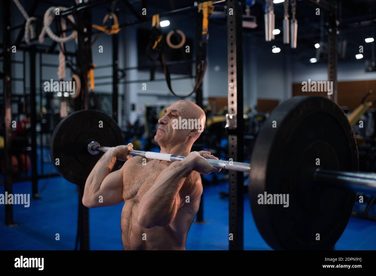 Potente atleta anziano in grande forma che si muove pulito e a scatti esercitarsi con il barbell pesante durante l'allenamento di sollevamento pesi in palestra Foto Stock