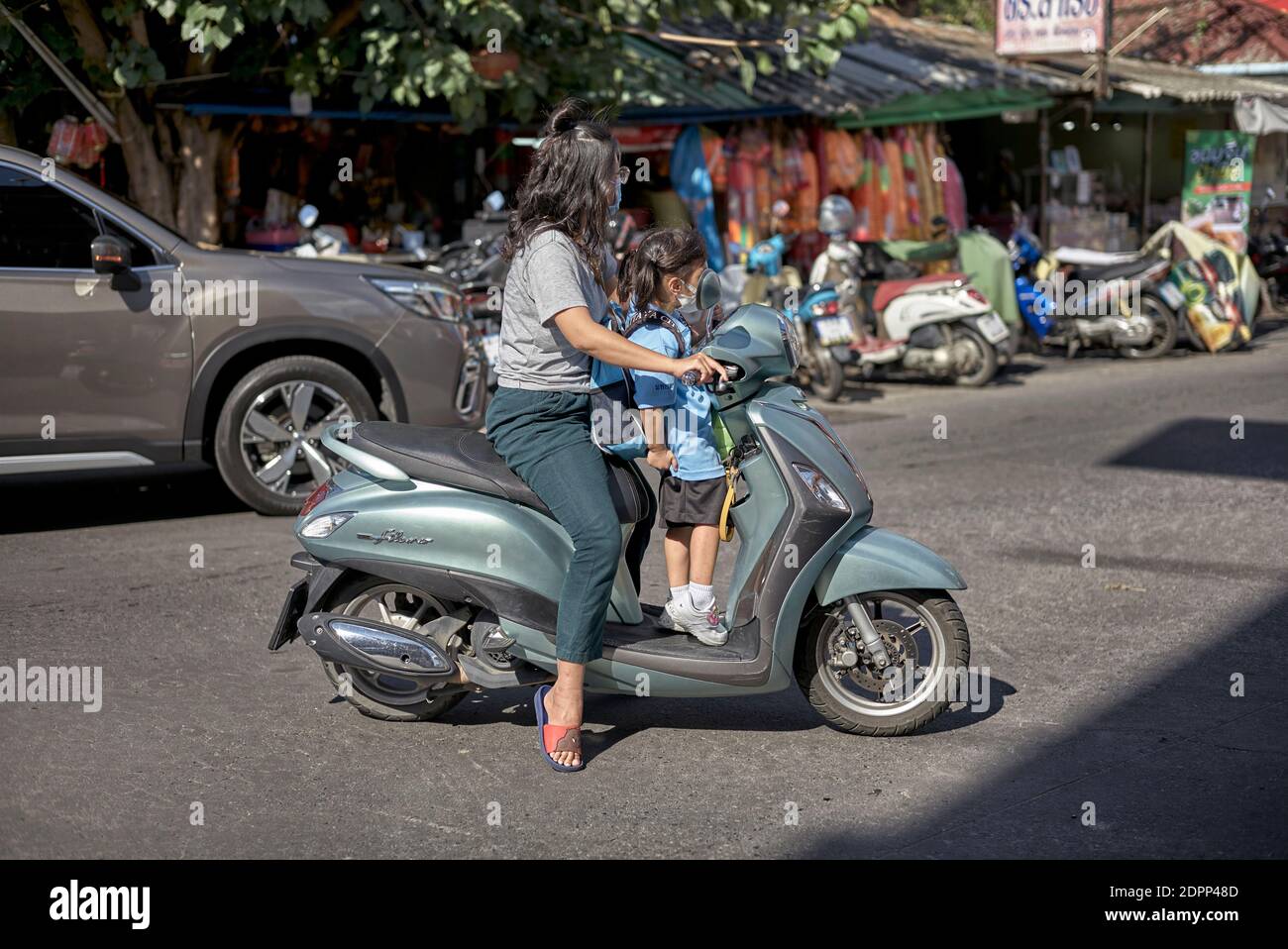 Thailandia persone moto. La scuola della Thailandia corre con la madre che trasporta il bambino in moto. Sud-est asiatico. Foto Stock