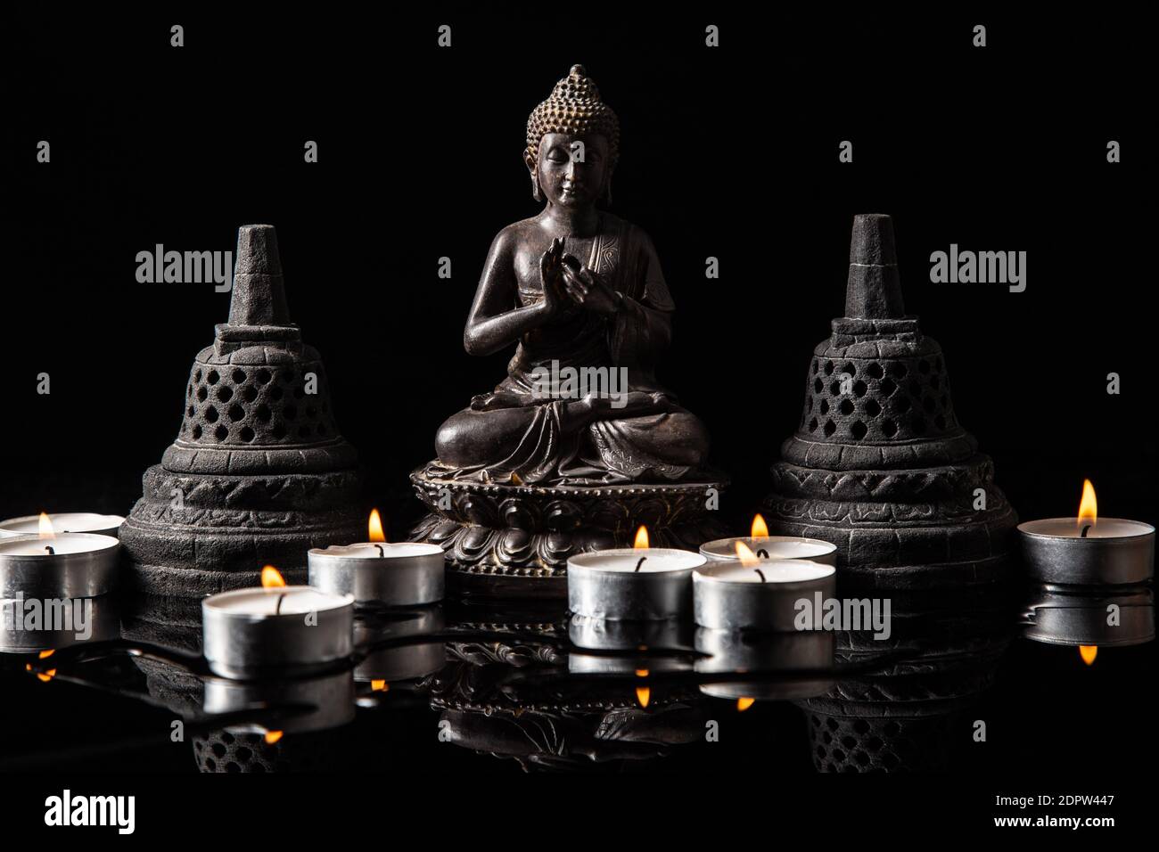 Statua di Buddha seduta in meditazione, con candele e campane buddiste . Zen e meditazione concetto. Foto Stock