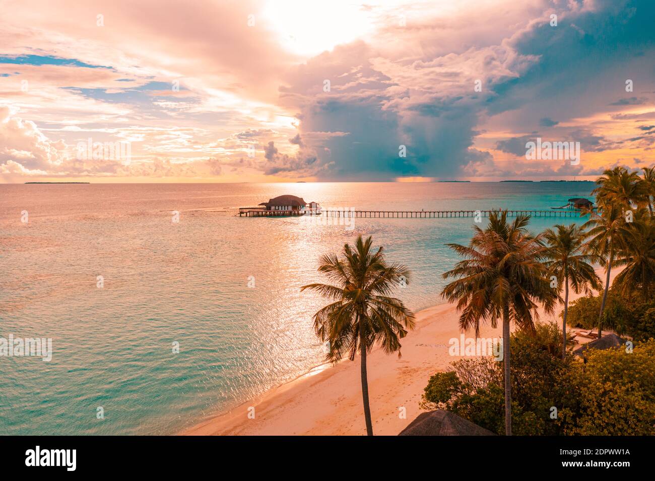 Alba aerea tramonto spiaggia baia vista, cielo colorato e nuvole, jetty legno sopra l'acqua bungalow. Meditazione relax tropicale vista drone, mare oceano Foto Stock