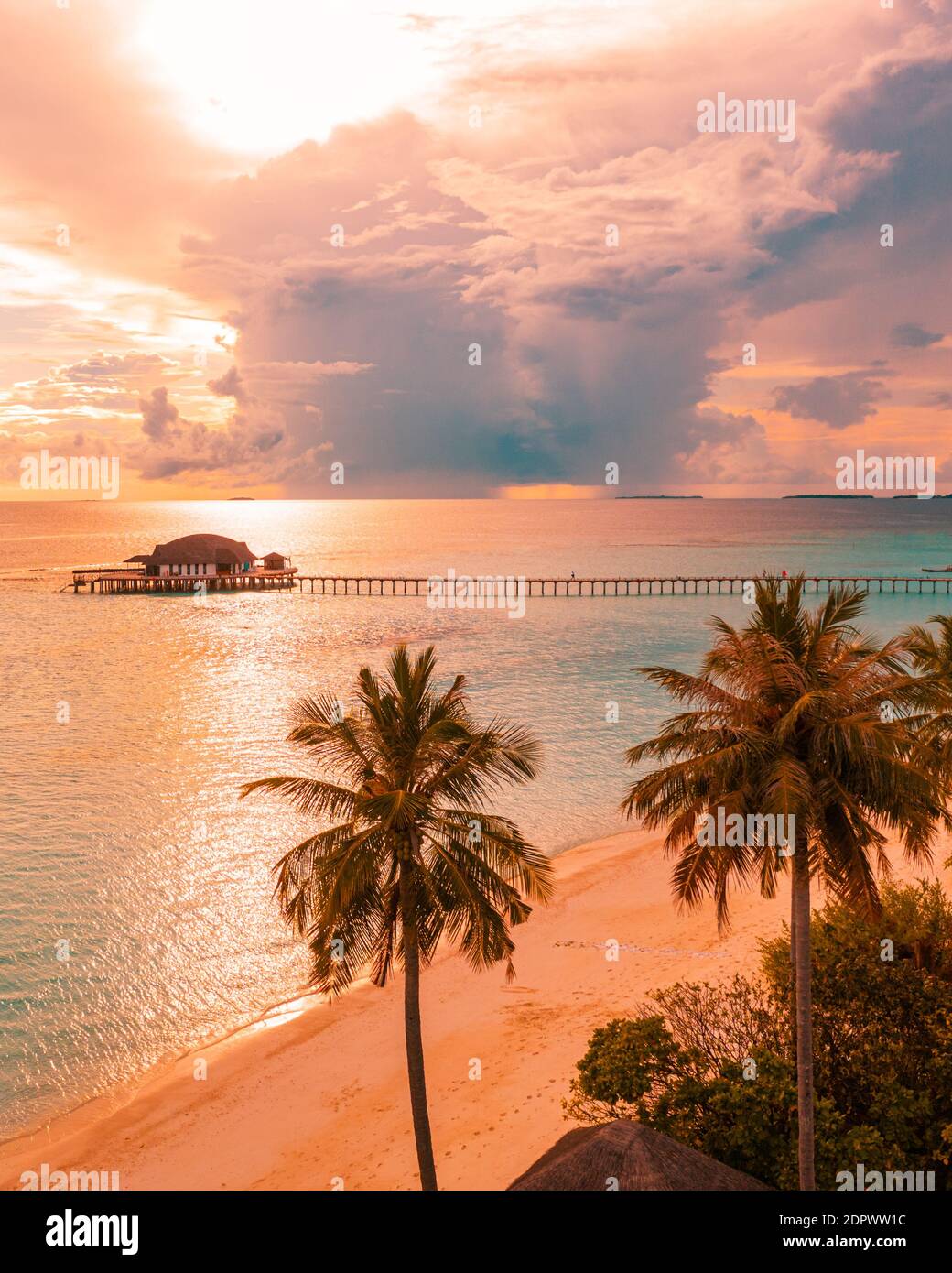 Alba aerea tramonto spiaggia baia vista, cielo colorato e nuvole, jetty legno sopra l'acqua bungalow. Meditazione relax tropicale vista drone, mare oceano Foto Stock
