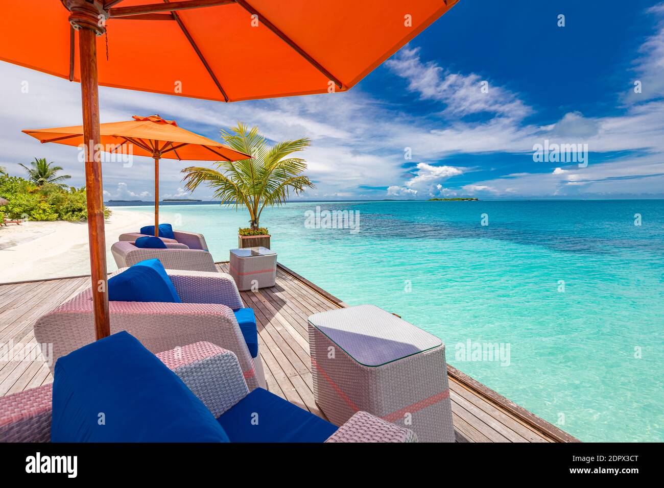 Sedie a sdraio in legno sotto ombrelloni con vista sull'oceano sull'isola tropicale. Resort di lusso estate, relax atmosfera, vacanza viaggio paesaggio Foto Stock