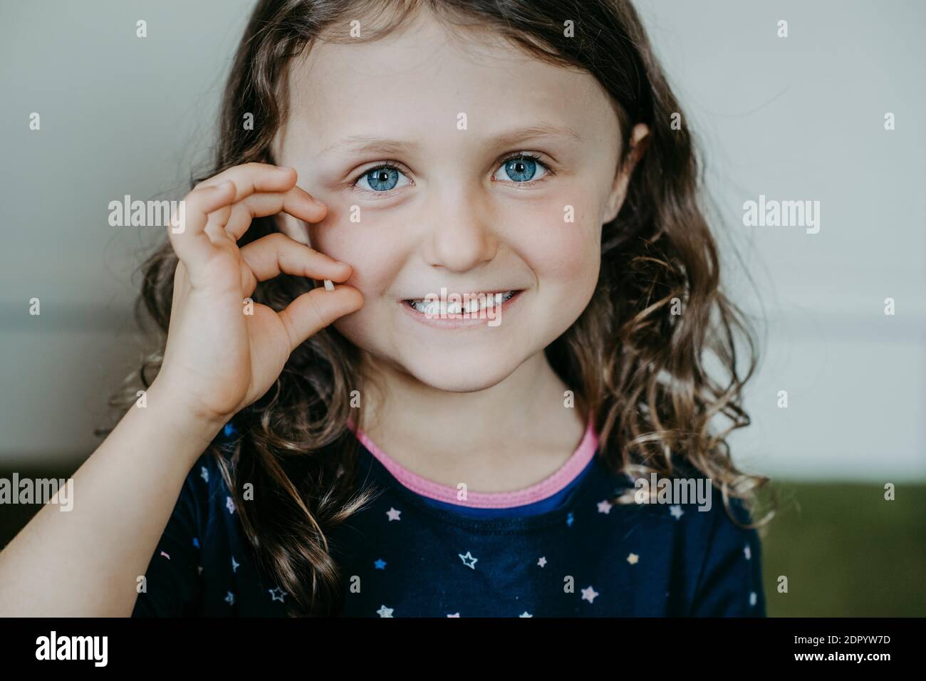 Ragazza con distanza tra i denti e dente in mano Foto Stock