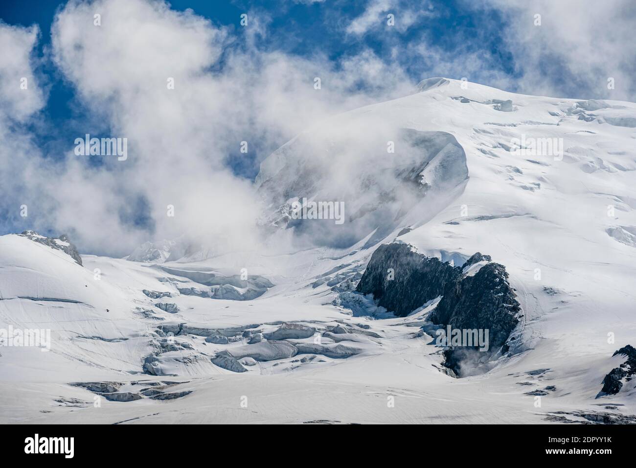 Alto paesaggio alpino di montagna, nuvole sulla cima Dome du Gouter con ghiacciaio, Chamonix, alta Savoia, Francia Foto Stock