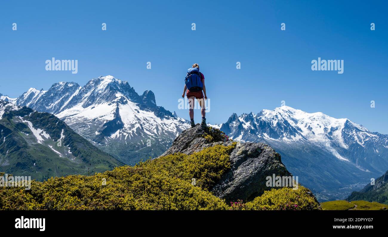 Escursionista in piedi su rocce, panorama di montagna da Aiguillette des Posettes, vetta sinistra di Aiguille Verte (a destra) Aiguille du Midi e Monte Bianco Foto Stock