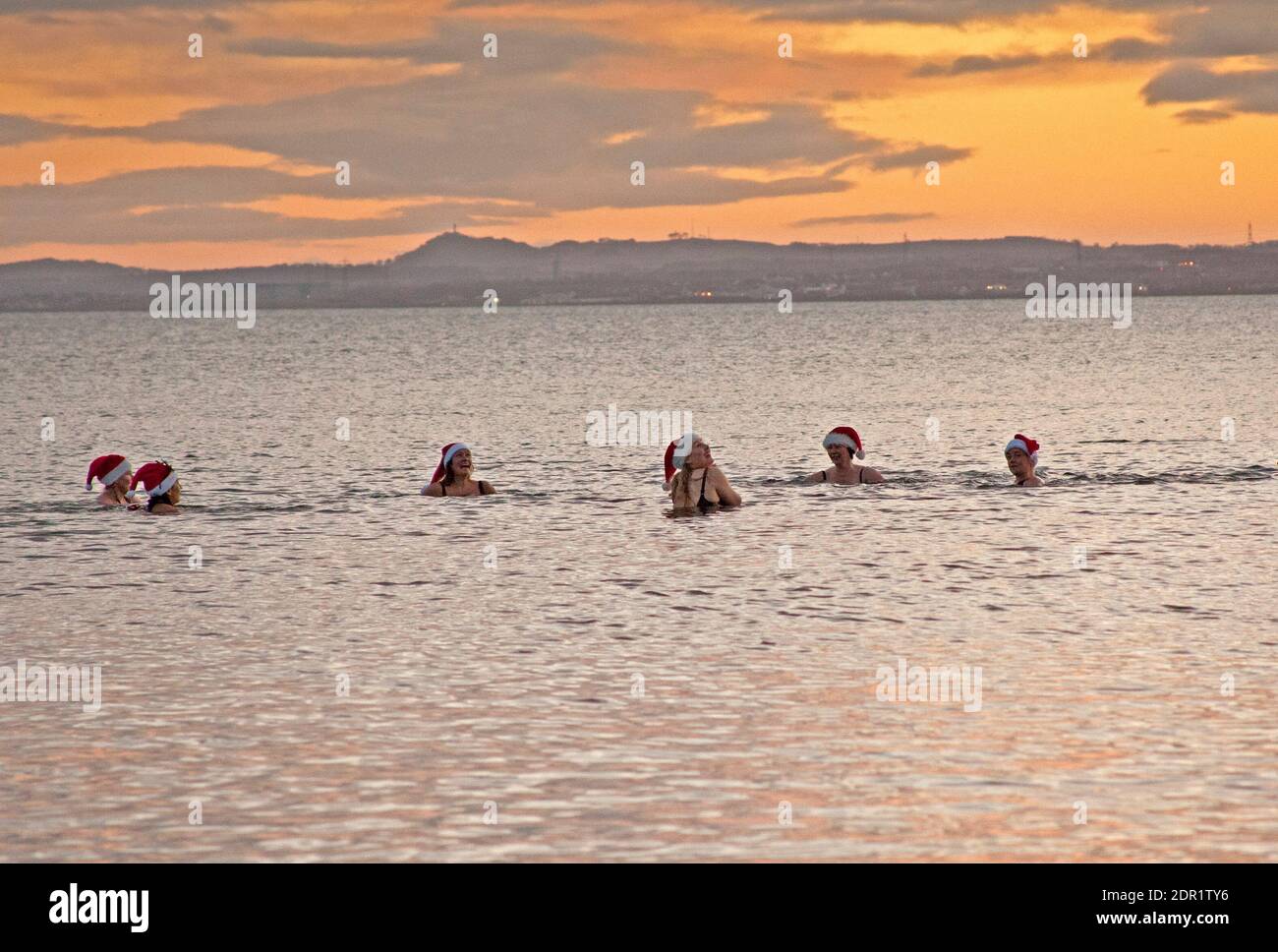 Portobello, Edimburgo, Scozia. REGNO UNITO. 20 dicembre 2020. Un gruppo di bagnanti con acqua fredda socialmente distanziati in Firth of Forth alla temperatura dell'alba di 6 gradi che tentano di rallegrare il loro umore con i cappelli di santa dopo la notizia della scorsa notte di ulteriori restrizioni di blocco Covid-19 aumentate durante il periodo festivo. Credit: Arch White/Alamy Live News Foto Stock