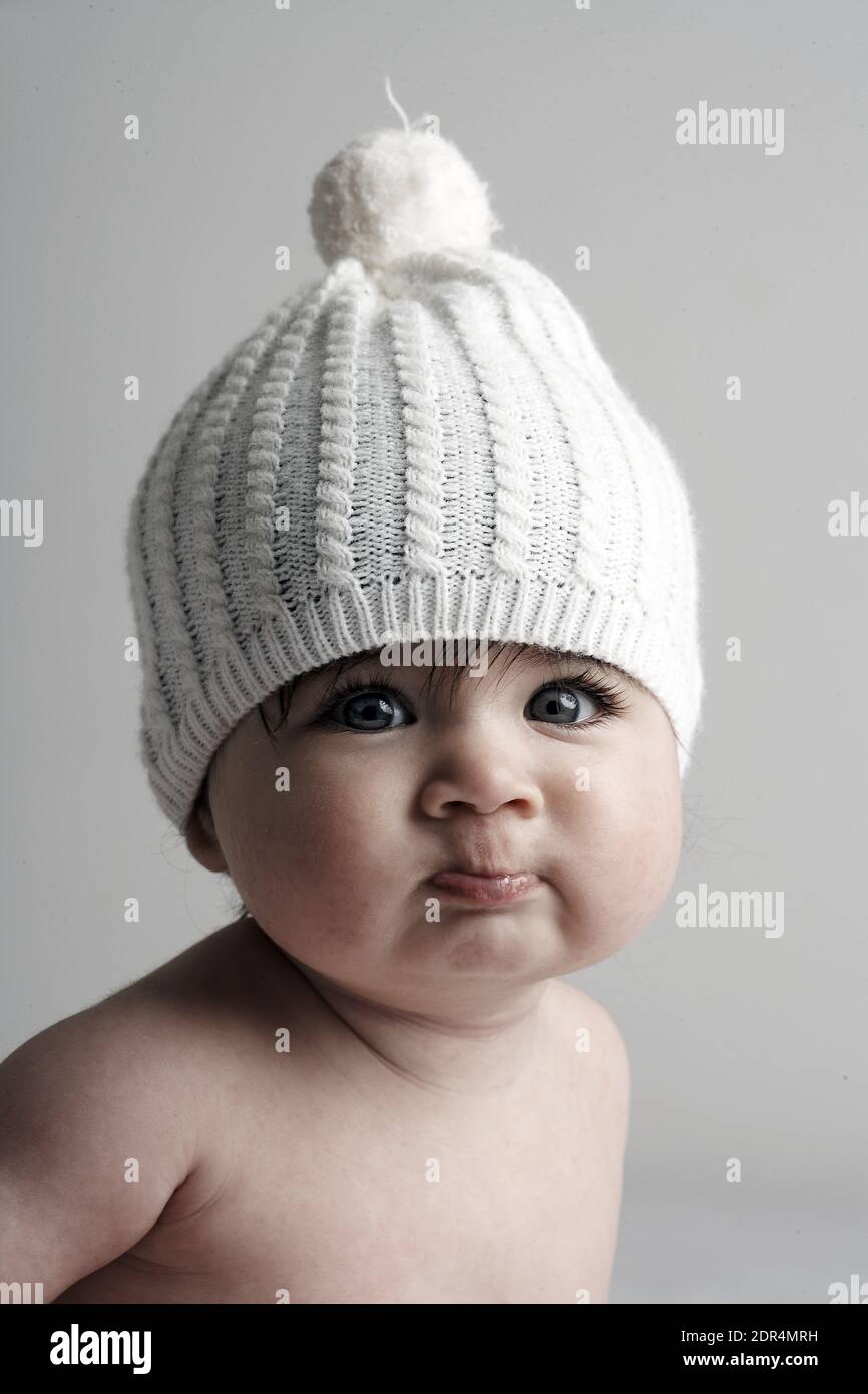 GRAN BRETAGNA / Inghilterra / Londra / Baby girl / 6-11 mesi /indossando maglia hat.on sfondo bianco Foto Stock