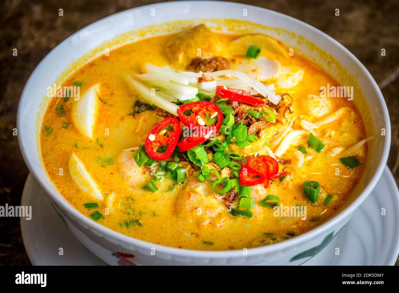 una ciotola di tagliatelle di riso laksa con salsa di curry dolce con germogli di fagioli d'uovo sode, capesante, puffs di tofu e torta di pesce Foto Stock