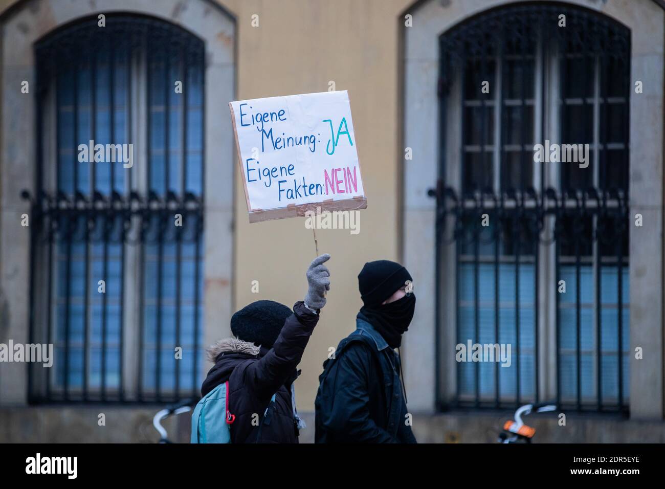 Berlino, Germania. 20 dicembre 2020. Due contro-dimostranti camminano accanto a una "marcia silenziosa" contro la politica di Corona dello stato vicino ad Alexanderplatz. Il loro segno recita 'opinione propria: Sì. Fatti propri: No. Credit: Christoph Soeder/dpa/Alamy Live News Foto Stock