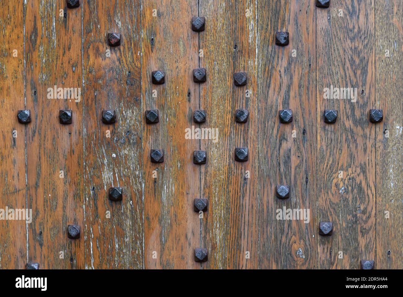 Primo piano di una porta in legno rustico dal design vintage con rivetti in metallo decorativi Foto Stock