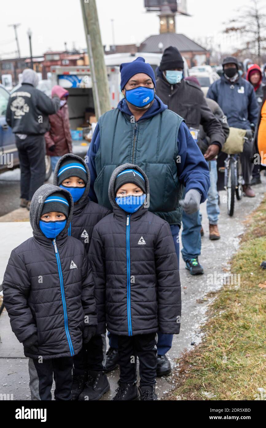 Detroit, Michigan, Stati Uniti. 19 dicembre 2020. Nella settimana prima di Natale, i volontari consegnano cibo alle persone bisognose, la maggior parte dei quali senza tetto, nel Roosevelt Park di Detroit. Una famiglia con tre ragazzi attende in fila per raccogliere il cibo. Credit: Jim West/Alamy Live News Foto Stock