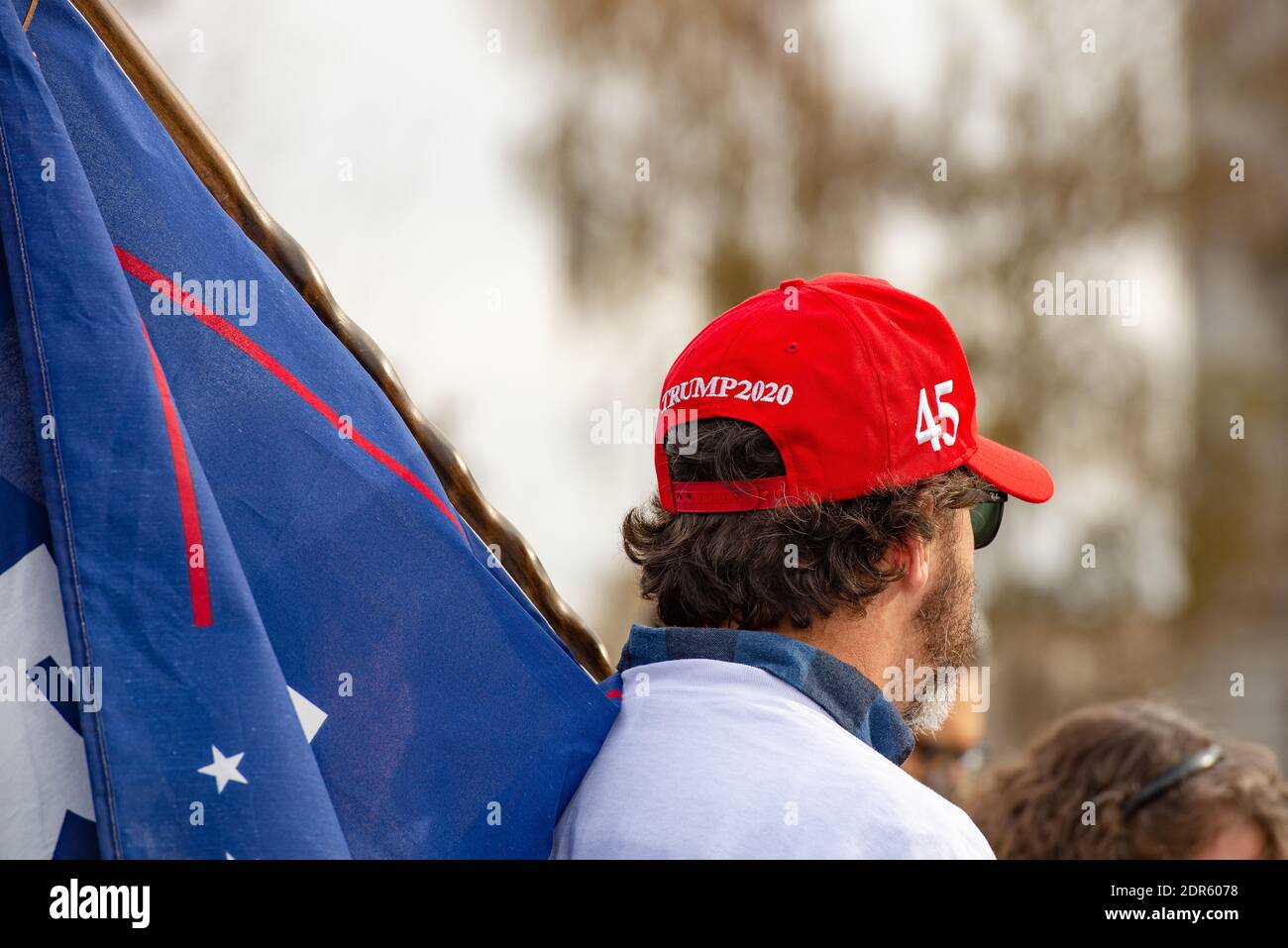 Helena, Montana / 7 novembre 2020: Uomo bianco che indossa il cappello rosso di Trump 2020 MAGA che tiene la bandiera di Trump alla fermata del rally rubato nella città capitale del Montana, re Foto Stock