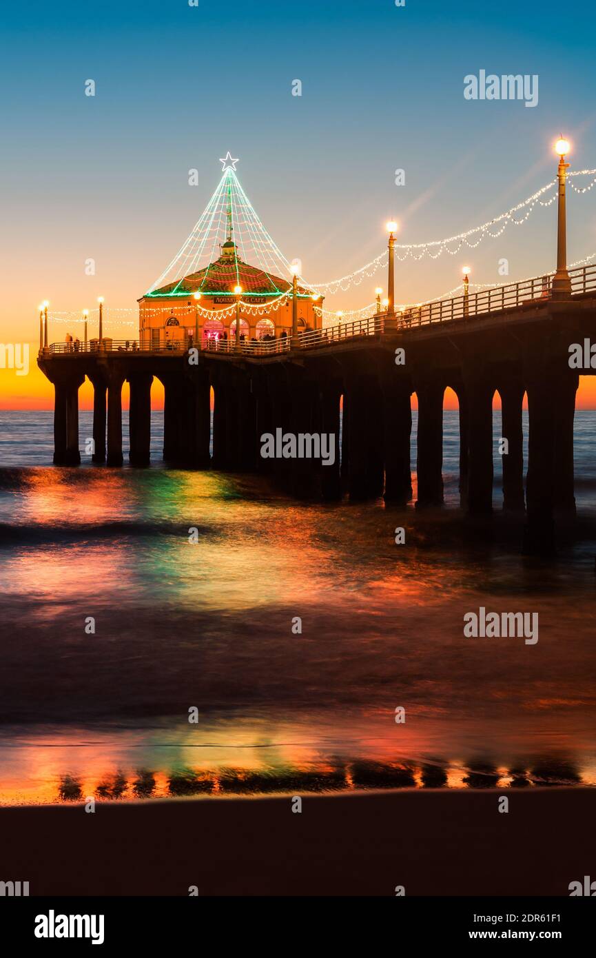 Scatto verticale del molo di Manhattan Beach fotografato illuminato dopo il tramonto durante il periodo natalizio a Manhattan Beach, California. Foto Stock