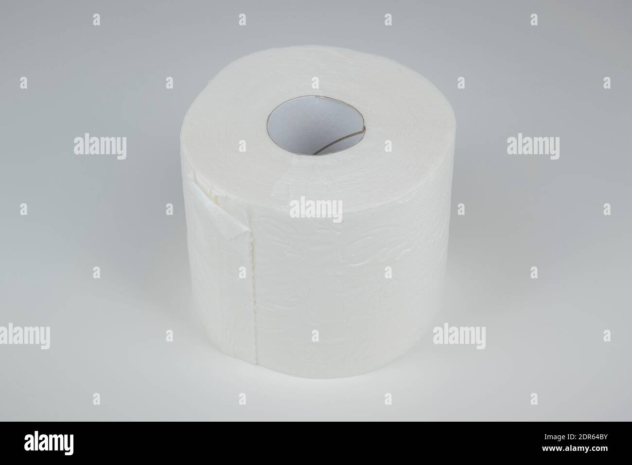 Eine Rolle Toilettenpapier auf weißem, neutralem Hintergrund. Foto Stock