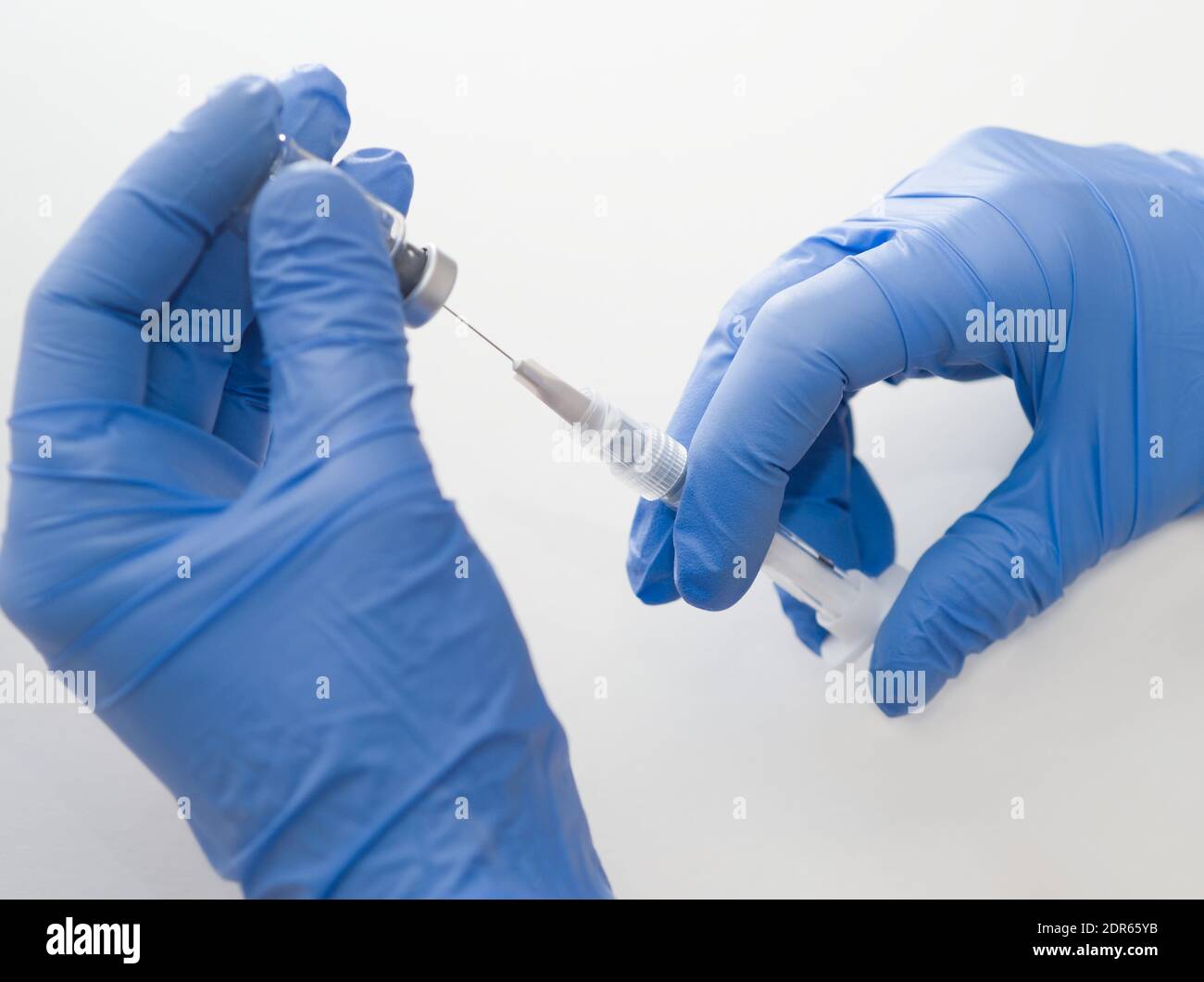Guanti in gomma blu con siringa e flacone per uso medico Primo piano su sfondo bianco Foto Stock