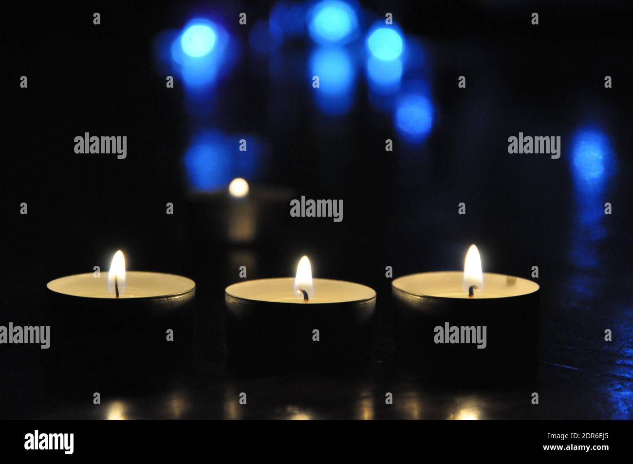 Candele di Natale che bruciano di notte. Luce dorata della fiamma della candela. Decorazione, nero.Abstract candele sfondo. Foto Stock