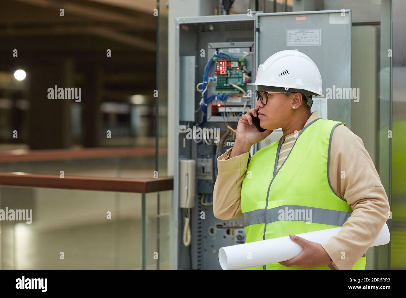 Vista laterale ritratto di una donna ingegnere che parla da smartphone durante l'ispezione del cantiere, spazio di copia Foto Stock