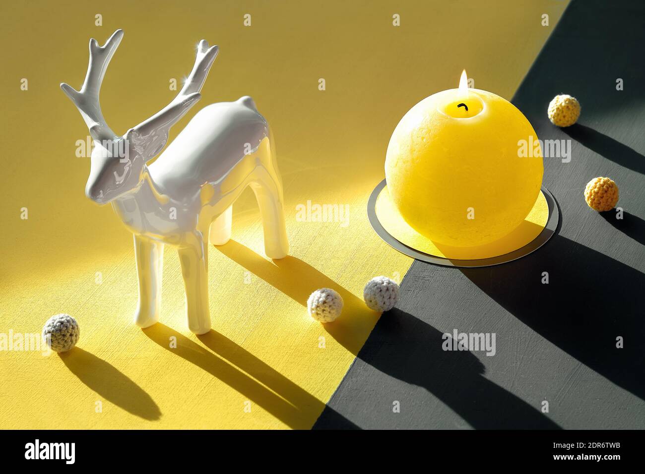 Giallo luminoso e grigio estremo, colori dell'anno 2021. Cervi, candele brucianti, fiori di cotone e palle su sfondo grigio giallo diviso. Foto Stock