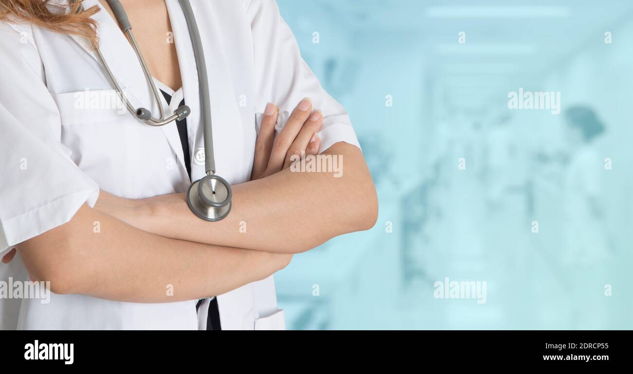 Foto a metà corpo di dottore femminile, senza viso, in piedi con le braccia piegate sul colore blu dell'ospedale per sfondo. Foto Stock