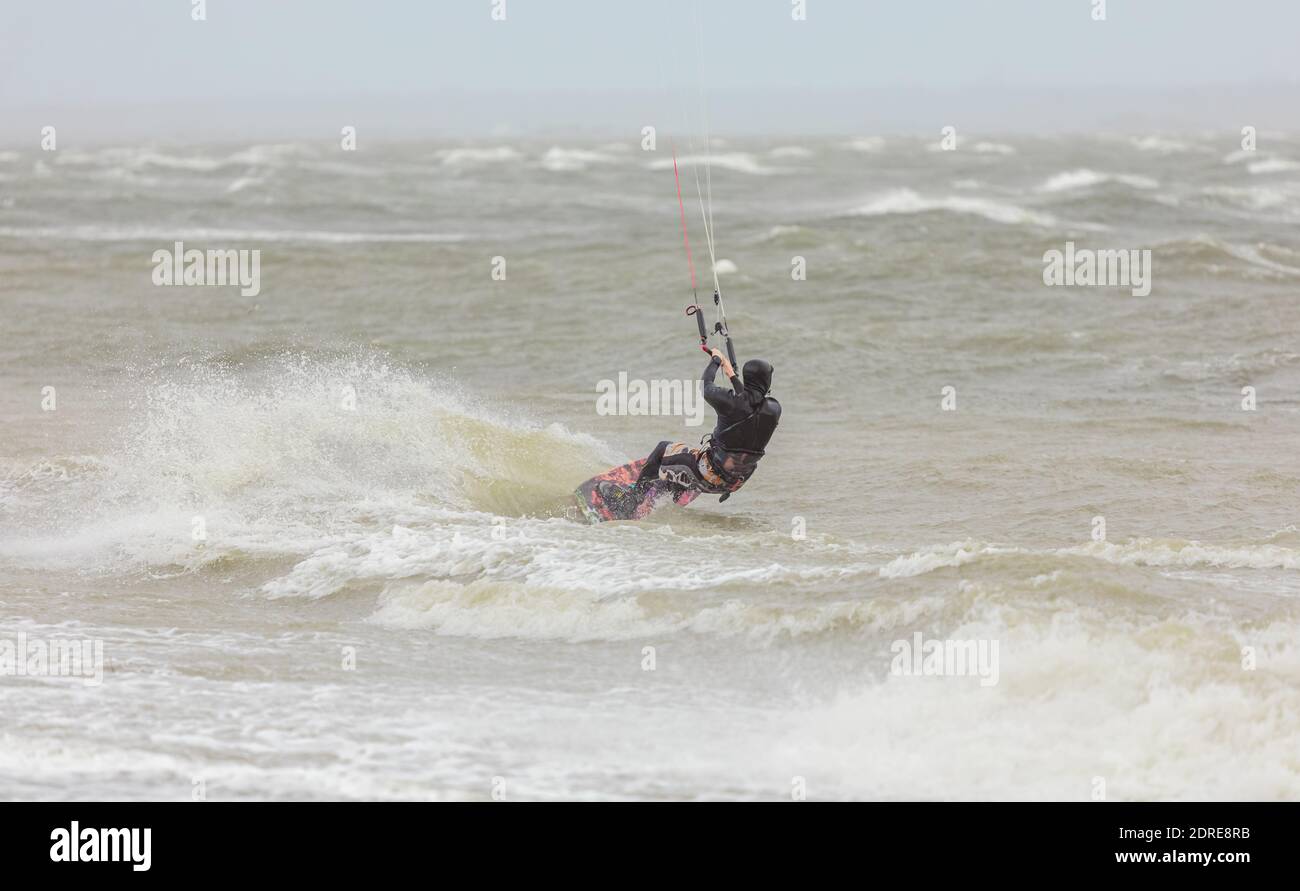 Un kiteboarder che cavalcano le onde in mare in una giornata piovosa. Boundary Bay, BC, Canada - Novembre 17,2020. Messa a fuoco selettiva, foto sportive, foto di viaggio. Foto Stock