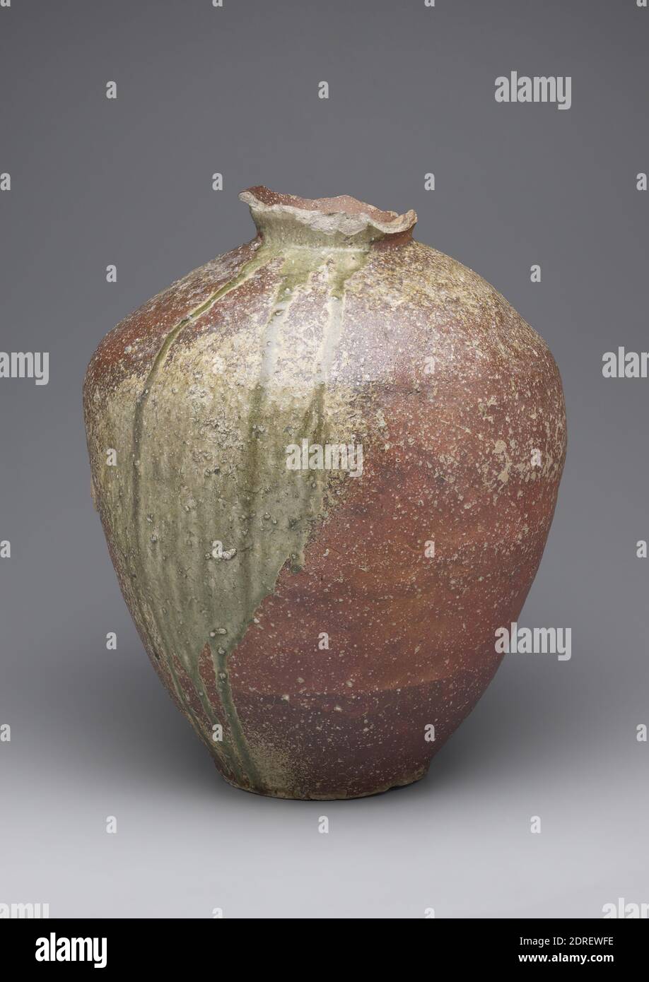 Vasetto, 15 ° secolo, gres con glassa di cenere naturale (Shigaraki ware), 21 7/16 poll. (54.5 cm), questo grande vasetto di stoccaggio della Valle di Shigaraki, a sud-est di Kyoto, incarna un'estetica integrale alla ceramica giapponese. Il vaso, realizzato a spirale in sezioni, dimostra il classico carattere Shigaraki, che è definito da una superficie ruvida e ruggine-arancio combinato con uno smalto naturale di frassino verde oliva che scorre dal collo stretto e sulle spalle rigonfianti al piede. L'alto contenuto di ferro dell'argilla conferisce al corpo la sua tonalità rossastra Foto Stock