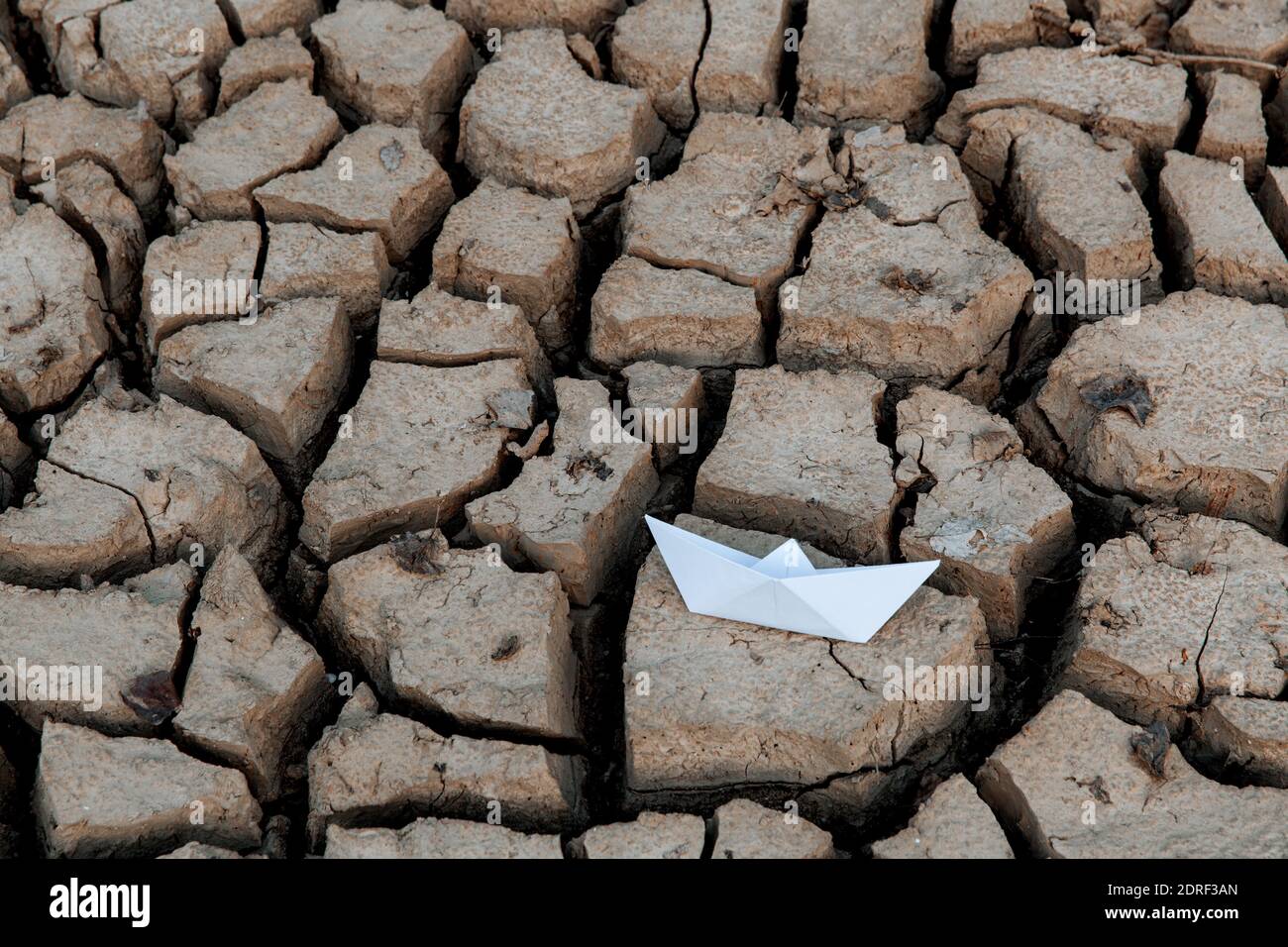 Nave di carta sul lago asciutto, siccità concettuale, riscaldamento globale. Foto Stock