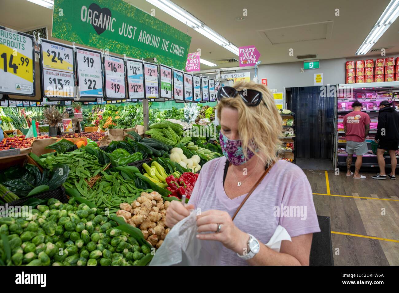 Modello rilasciato donna australiana indossare facemark come protezione covid 19 Negozio di alimentari nel supermercato Sydney per le verdure Foto Stock