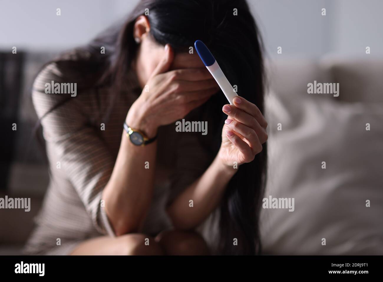 Donna triste che tiene il test di gravidanza in mano Foto Stock