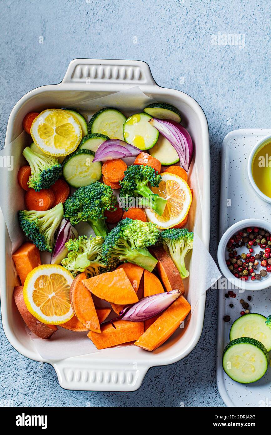 Verdure crude tritate - patate dolci, zucchine, broccoli e carote in un arrosto di piatto. Cottura delle verdure per la cottura in forno. Cucinare sano fo Foto Stock
