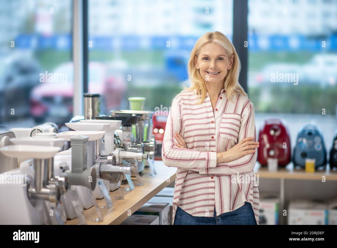 Bionda cliente femminile in piedi in uno showroom di beni di consumo e. aspetto contento Foto Stock