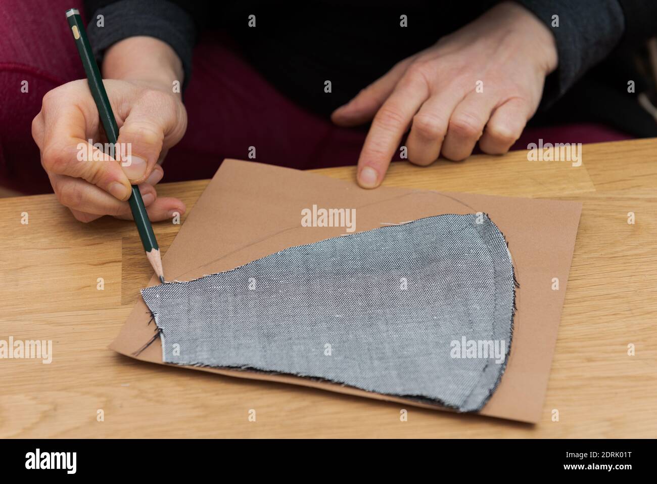 Mani umane che disegnano un modello principale con la matita di piombo sopra cartone per la realizzazione di maschere facciali di protezione a casa durante il blocco Della crisi di Covid Foto Stock