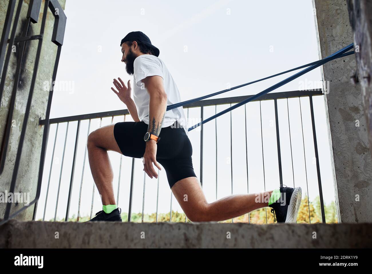 Atleta maschile concentrato che corre sulle scale per rendere l'allenamento più intensivo. Sportivo bello giovane uomo allenarsi da solo all'aperto. Punto di allenamento per scale Foto Stock