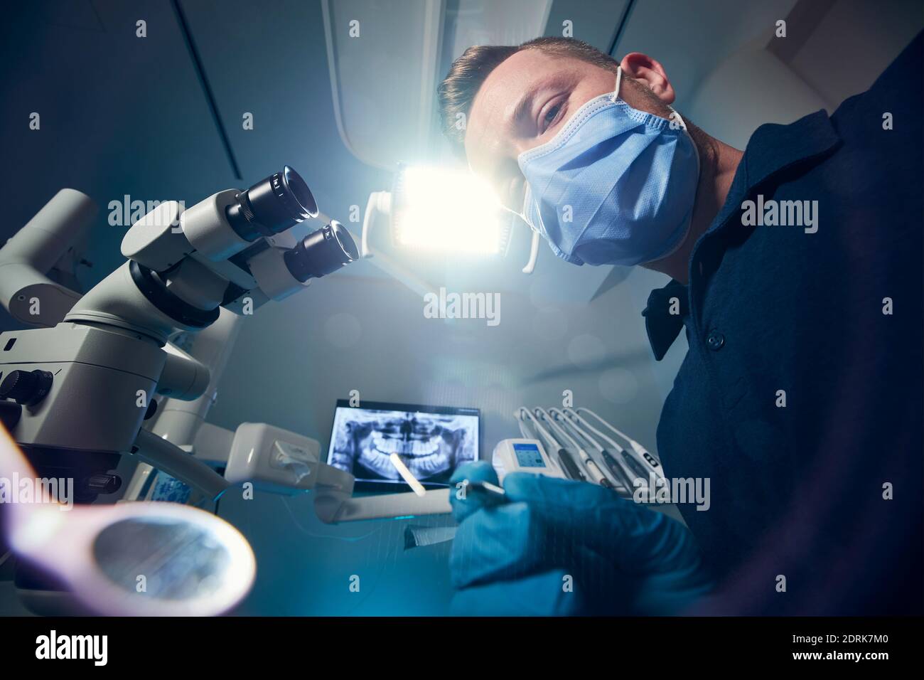 Dentista che esamina il paziente con attrezzature dentali contro la moderna chirurgia dentale con raggi X e microscopio. Foto Stock