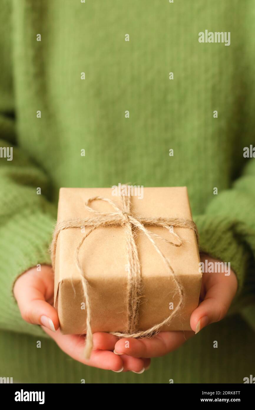Mani donne che tengono bel presente avvolto in carta nera e decorato con ramo verde, primo piano Foto Stock