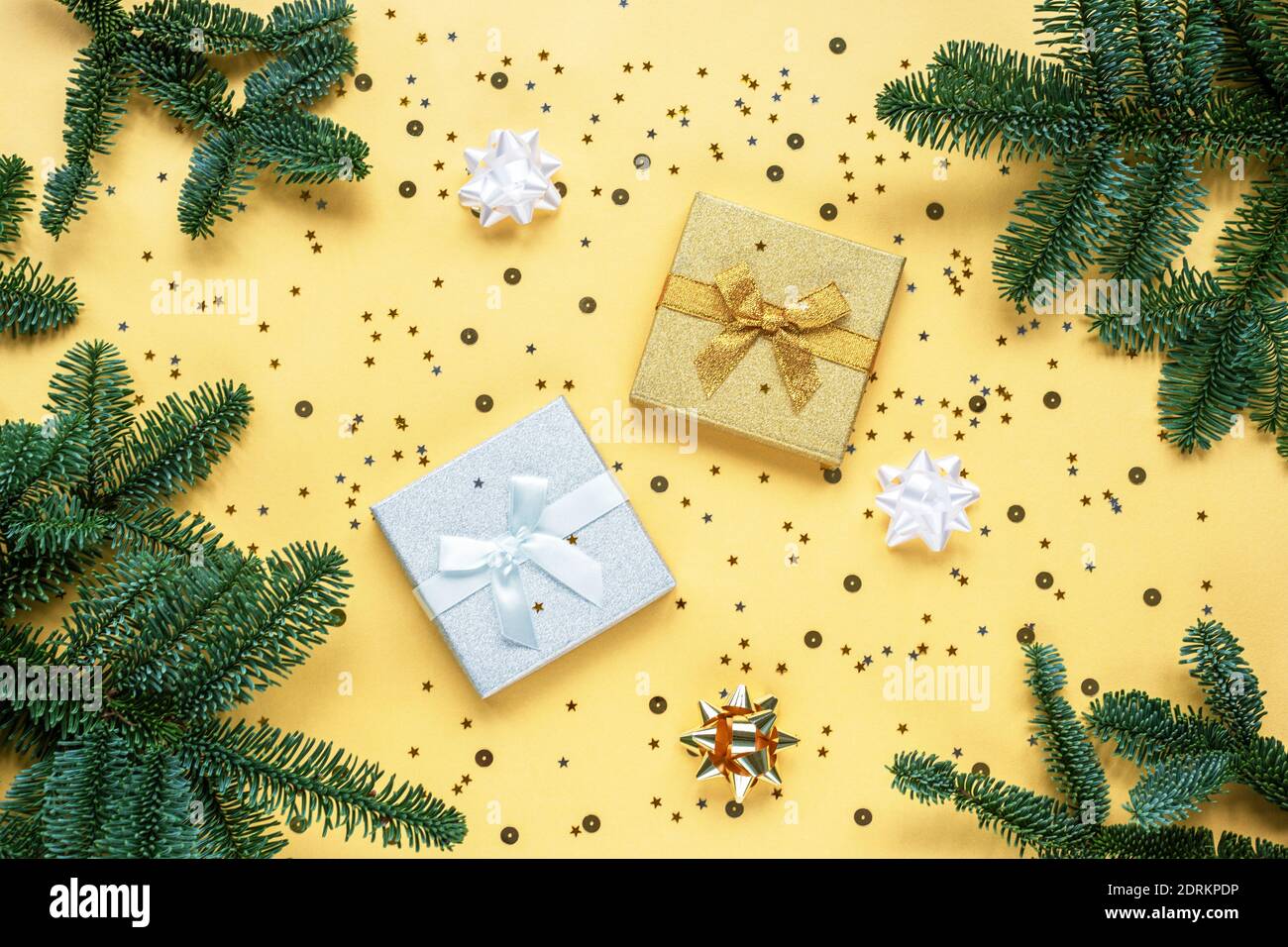 Due regali e rami di abete verde su sfondo giallo con confetti. Concetto di Natale. Vista dall'alto, disposizione piatta, spazio per la copia. Foto Stock