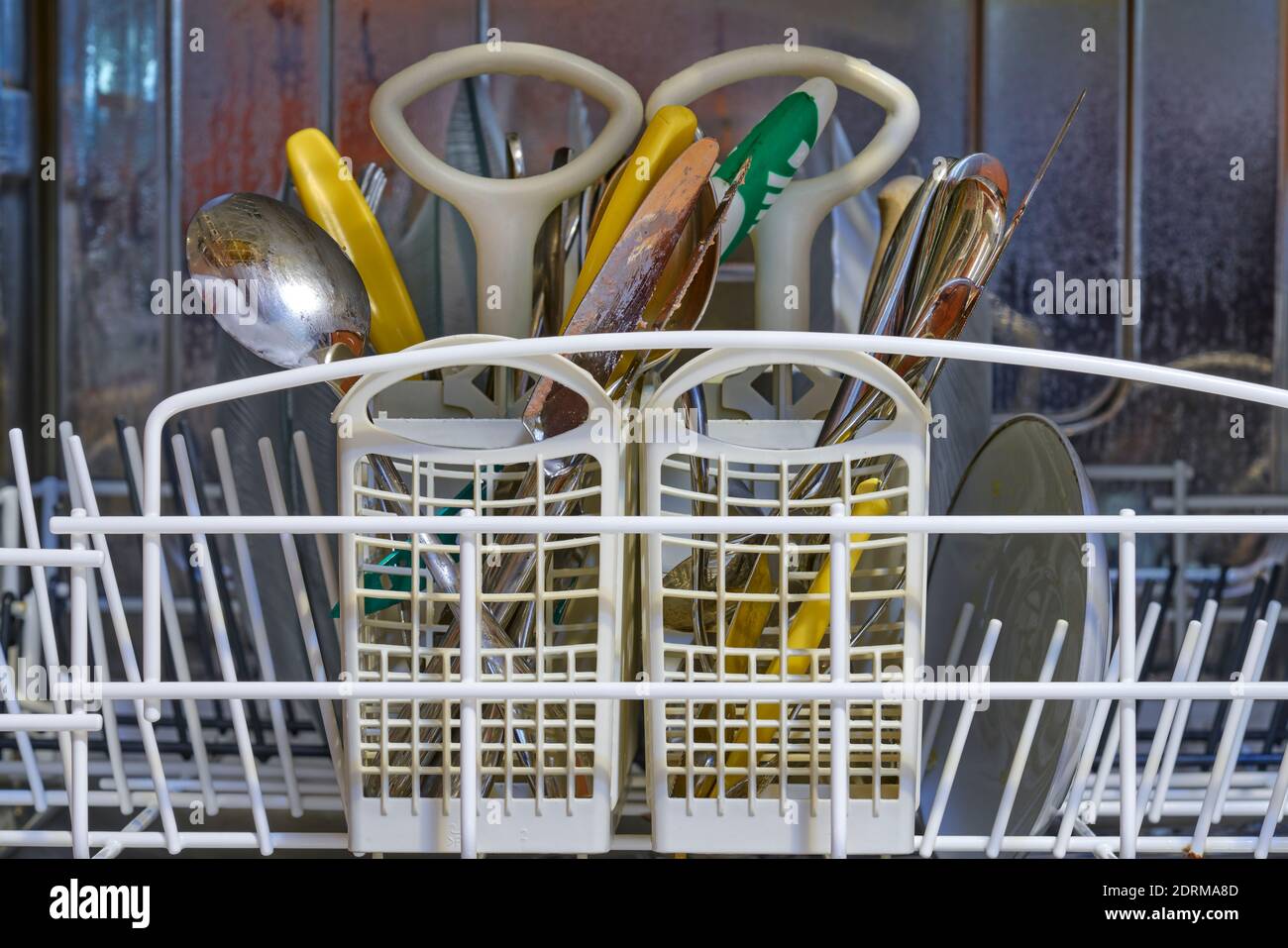 piastre, forcelle, cucchiai e coltelli sporchi in lavastoviglie in acciaio inox Foto Stock