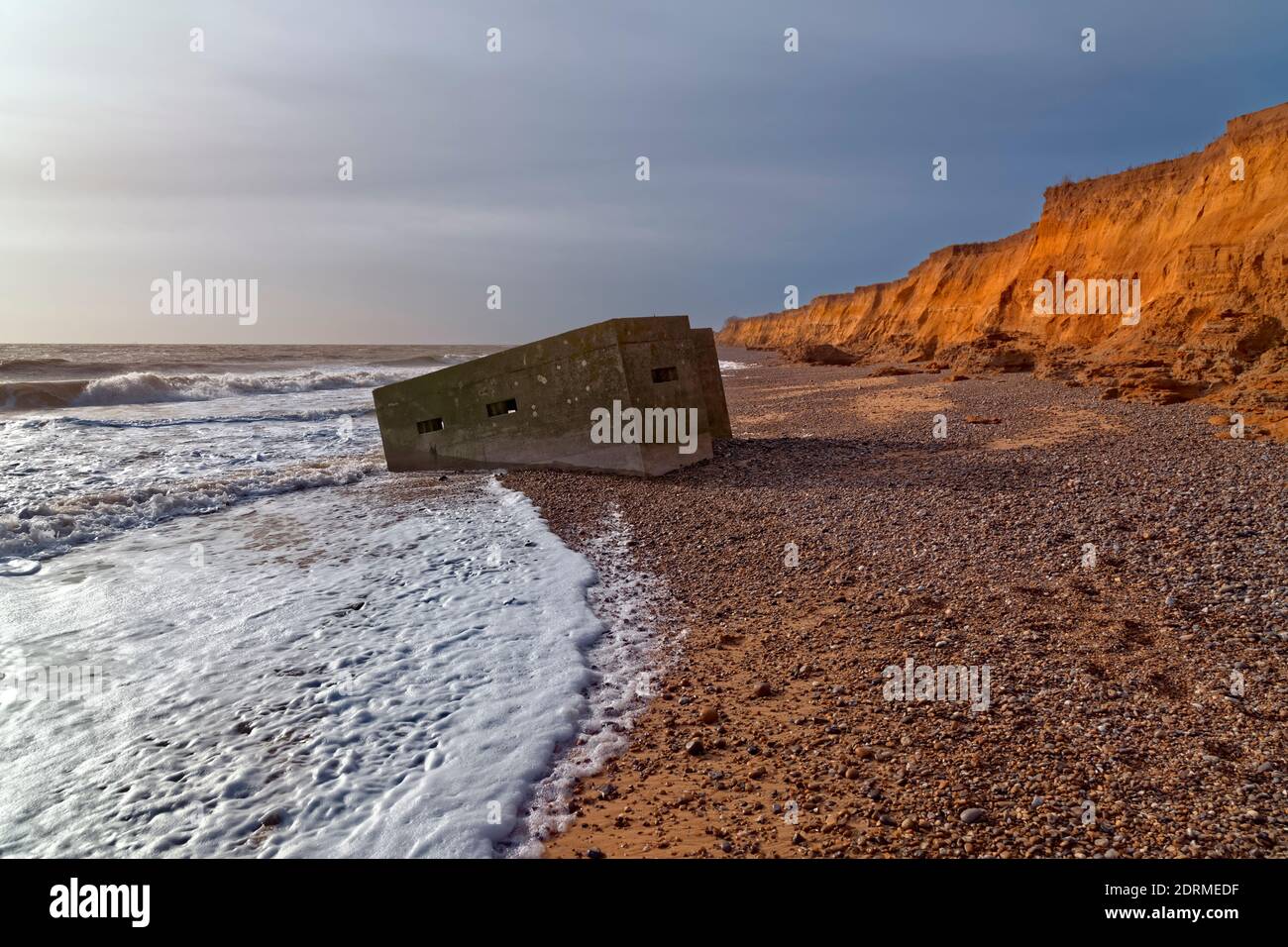 WW2 scatola di pillola lavata nel mare a causa di erosione costiera sulla costa di Suffolk, Inghilterra Foto Stock