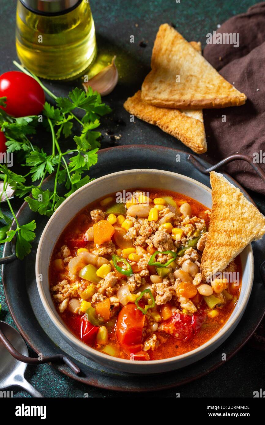 Cucina messicana tradizionale. Chili con carne macinata con verdure su tavola di pietra scura. Foto Stock