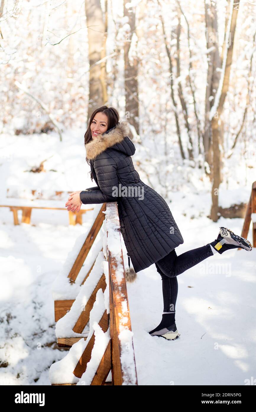 Giovane donna in posa in foresta innevata con cappotto caldo Foto Stock