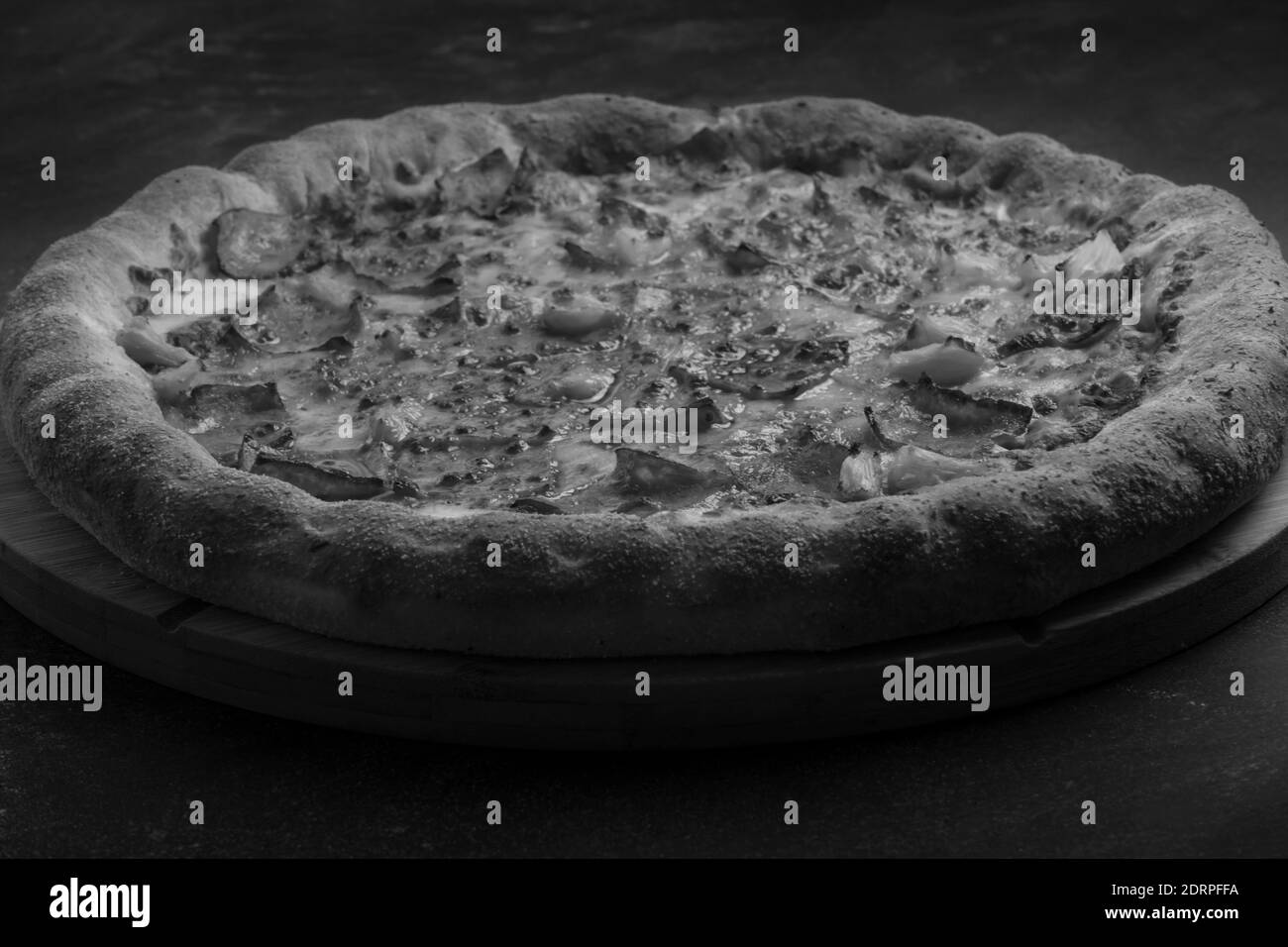Pizza bianca e nera con formaggio, pancetta croccante e ananas su fondo scuro. Foto Stock