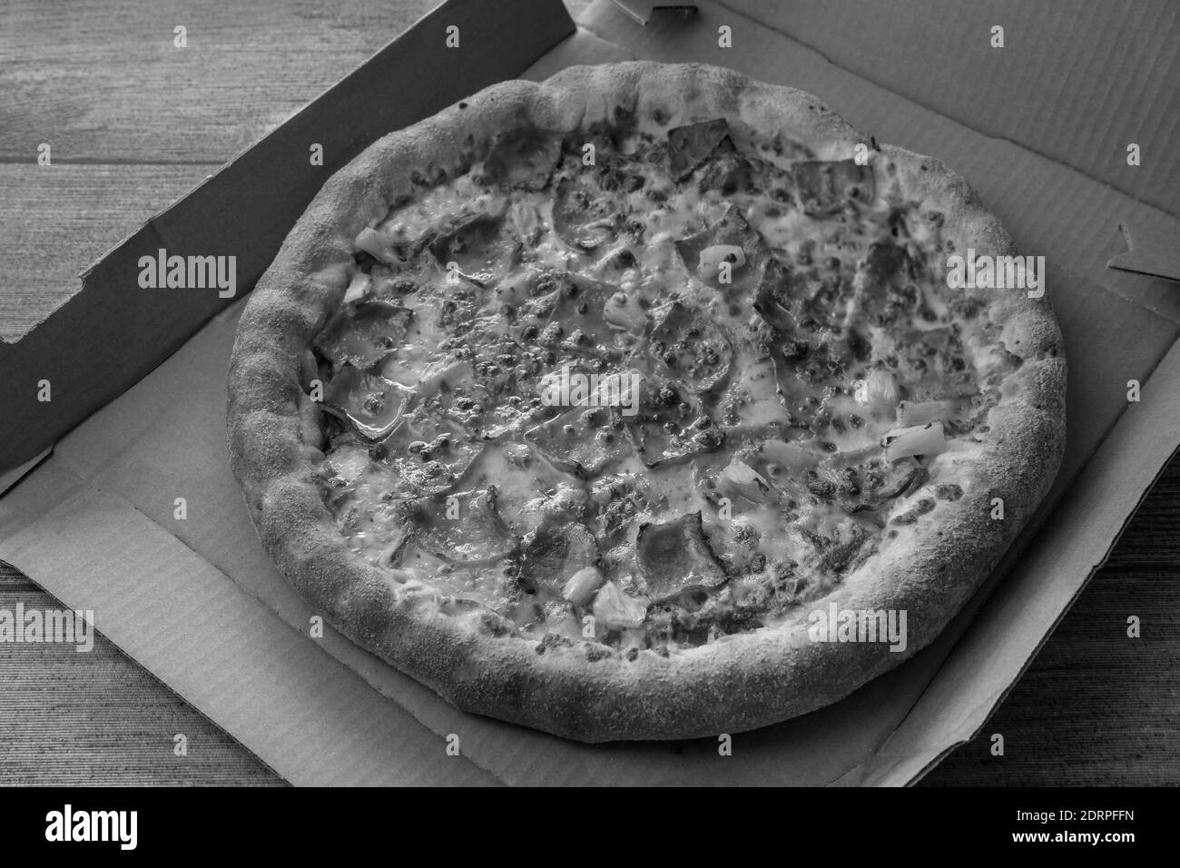 Deliziosa pizza fresca con pancetta, formaggio e ananas su scatola di cartone. Pizza hawaiana in stile bianco e nero. Foto Stock