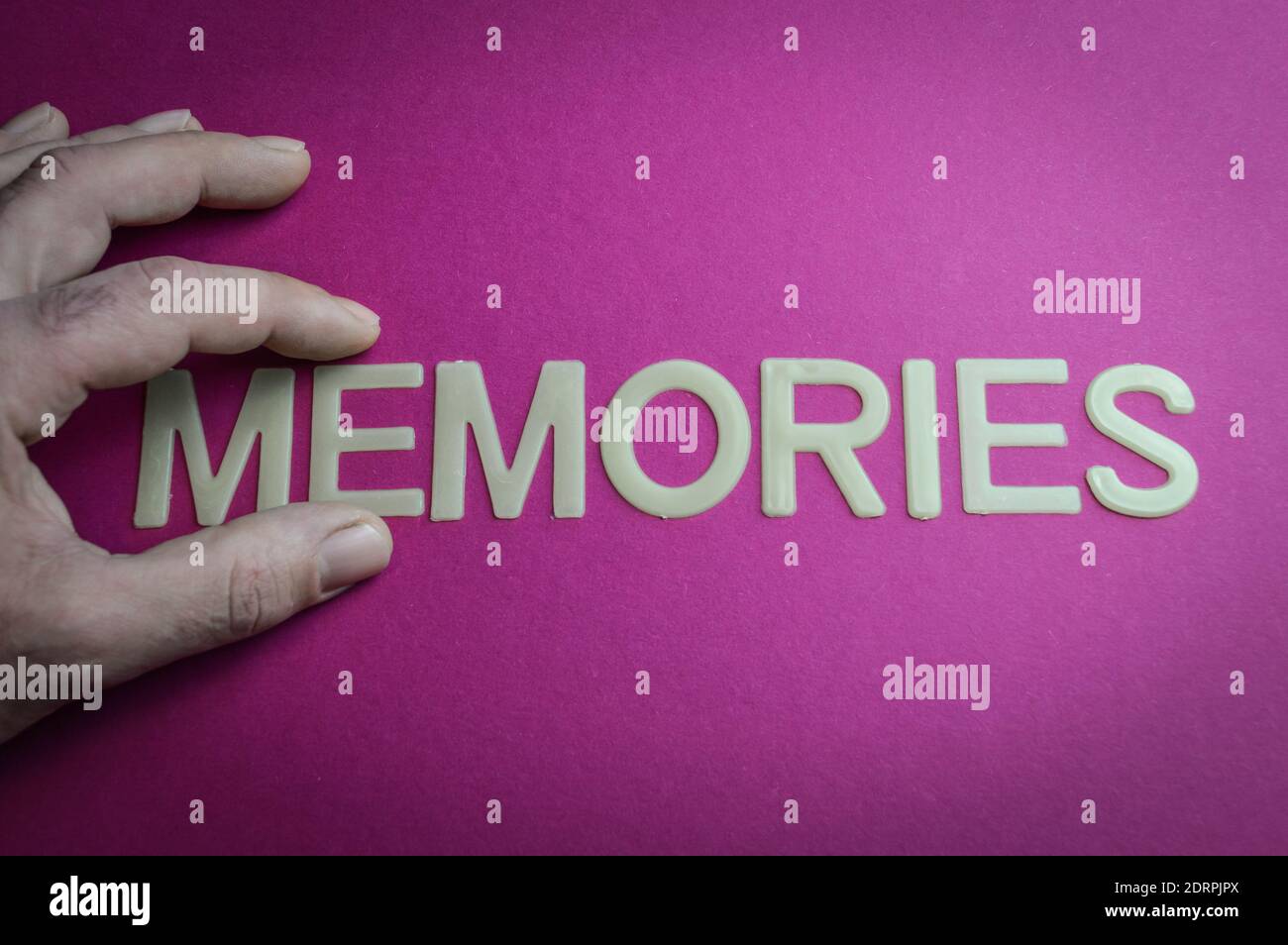 Dita umane che tengono le memorie di parola scritte con lettere di plastica su sfondo di carta rosa, concetto Foto Stock