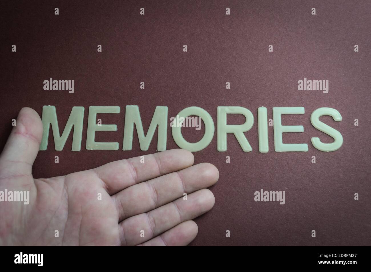 Mano umana che mostra le memorie di parola scritte con lettere di plastica su sfondo di carta marrone Foto Stock