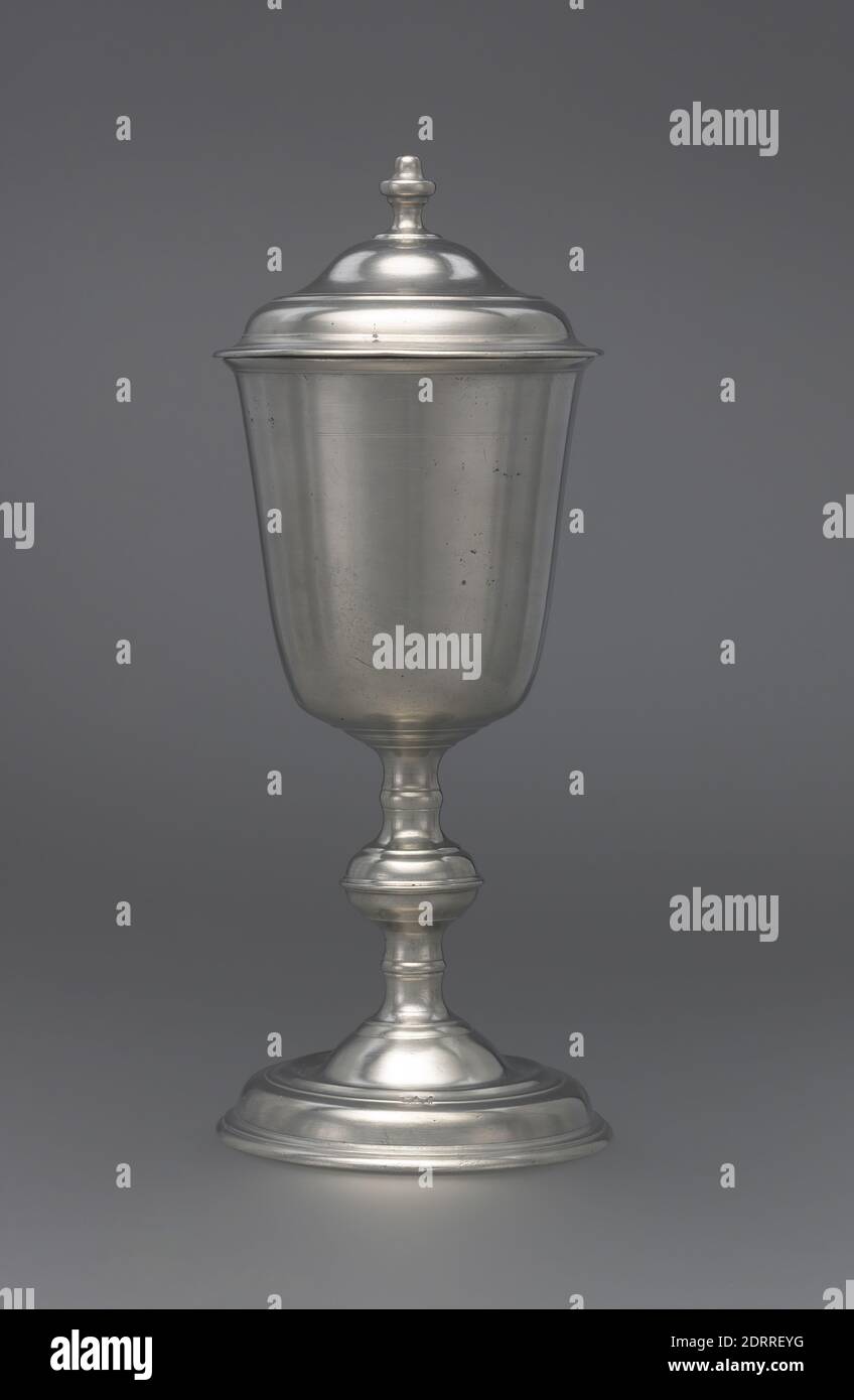 Produttore: Johann Christoph Heyne, americano, nato Germania, 1715–1781, Covered Chalice, Pewter, 11 1/16 pollici Johann Christoph Heyne, produttore di questo calice, era un ministro moravo che emigrò dalla sua nativa Germania in Pennsylvania nel 28.1. Non sorprende che la maggior parte del suo lavoro sopravvissuto come pelatore consista in oggetti utilizzati per celebrare l'Eucaristia nelle chiese luterane e morave nelle comunità di lingua tedesca intorno a Lancaster. Heyne si era addestrato come un pelatore in Svezia, dove ha assorbito lo stile barocco così superbamente espresso in questo calice coperto. Foto Stock