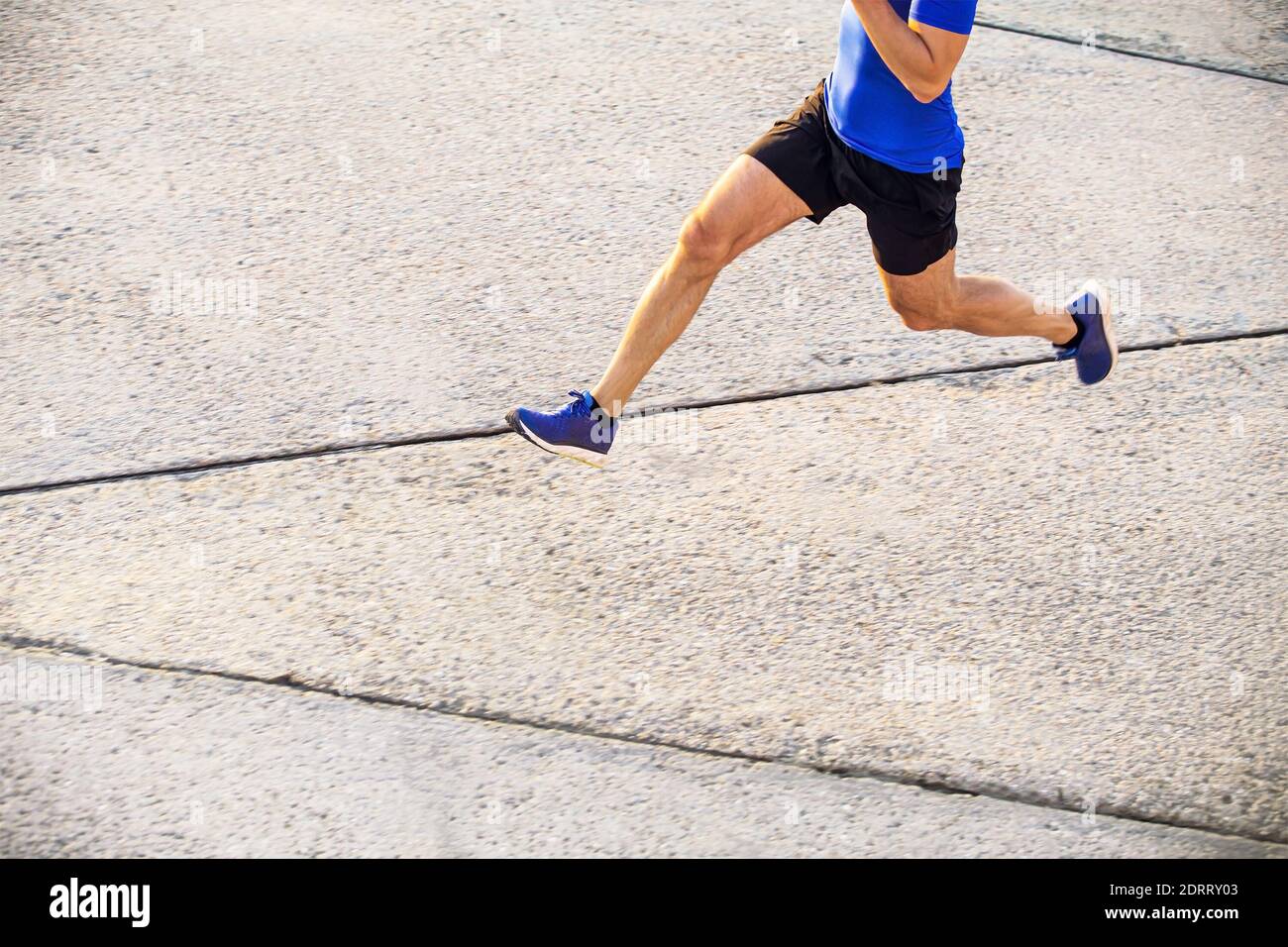 il corridore uomo corre su strada in cemento alla luce dell'alba Foto Stock