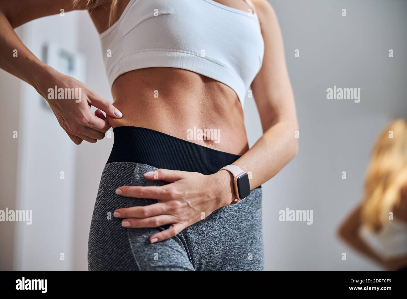 Donna non riconosciuta in abbigliamento sportivo che cerca la perdita di grasso addominale e peso loos Foto Stock