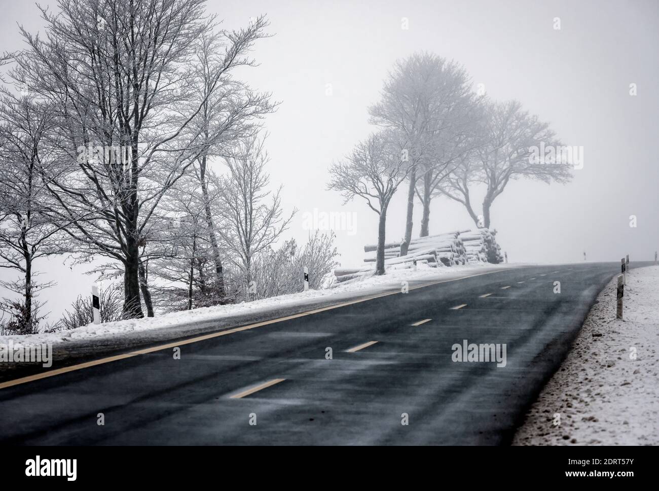 Winterberg, Sauerland, Renania Settentrionale-Vestfalia, Germania - paesaggio innevato con strada di campagna vuota. Foto Stock